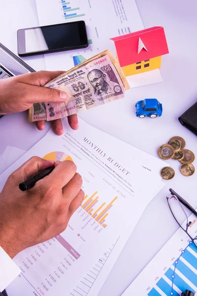 Hombre indio o contable persona que presenta formulario de declaración de impuestos indio o documento ITR que muestra moneda india, modelo de casa, coche de juguete y calculadora sobre mesa blanca, enfoque selectivo —  Fotos de Stock