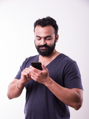 sakallı ve bıyıklı hipster hint genç adam akıllı telefon kullanarak meşgul, beyaz arka plan üzerinde izole