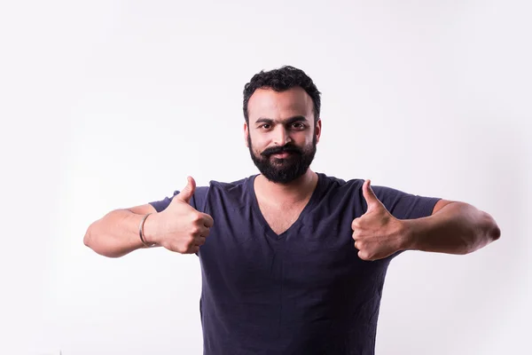 Хипстер индийский молодой человек с бородой и усами показывает знак успеха или большие пальцы вверх обеими руками, изолированные на белом фоне — стоковое фото