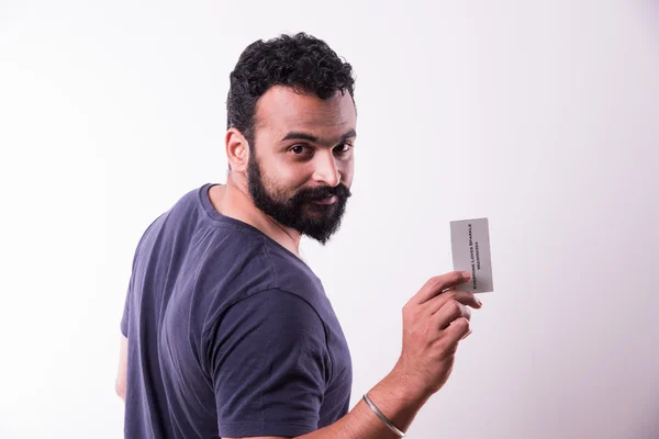 Jovem indiano hipster com barba e bigode exibindo cartão de visita vazio. feliz sorriso jovem bonito asiático cara desgaste camisa isolado branco fundo — Fotografia de Stock