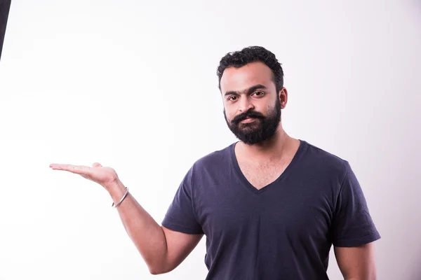 Индийский молодой человек с бородой представляет что-то, изолированное на белом фоне — стоковое фото