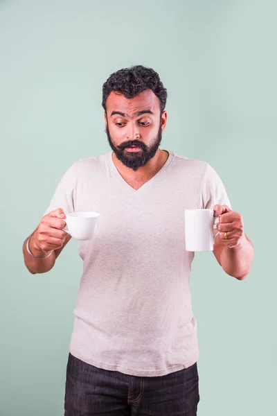 Homem indiano elegante com barba com duas xícaras de café em duas mãos olhando para a câmera . — Fotografia de Stock