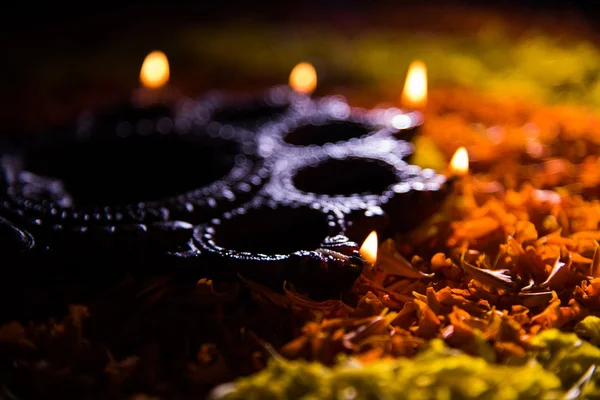 Tradicional diya o lámpara de aceite encendido en rangoli colorido compuesto de pétalo de flor, en el festival de luces llamado diwali o deepawali, enfoque selectivo —  Fotos de Stock