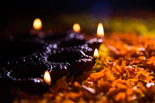 Lampada tradizionale a diya o olio accesa su colorati rangoli costituiti da petali di fiori, sulla festa delle luci chiamate diwali o deepawali, focus selettivo — Foto Stock