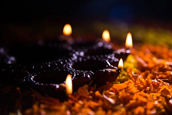 Lampe à huile ou diya traditionnelle allumée sur des rangoli colorés composés de pétales de fleurs, sur la fête des lumières appelée diwali ou deepawali, mise au point sélective — Photo