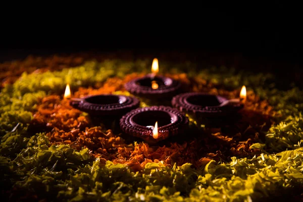 Lampe à huile ou diya traditionnelle allumée sur des rangoli colorés composés de pétales de fleurs, sur la fête des lumières appelée diwali ou deepawali, mise au point sélective — Photo