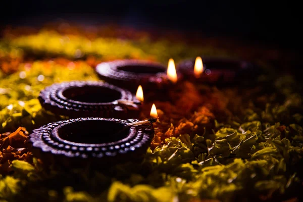 Lampada tradizionale a diya o olio accesa su colorati rangoli costituiti da petali di fiori, sulla festa delle luci chiamate diwali o deepawali, focus selettivo — Foto Stock