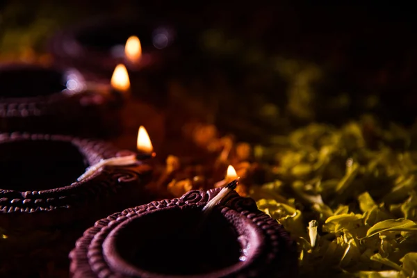 Lampada tradizionale a diya o olio accesa su colorati rangoli costituiti da petali di fiori, sulla festa delle luci chiamate diwali o deepawali, focus selettivo — Foto Stock