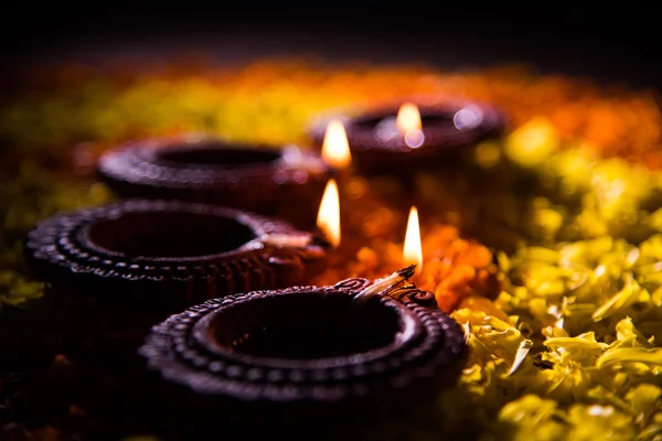 Lampada tradizionale a diya o olio accesa su colorati rangoli costituiti da petali di fiori, sulla festa delle luci chiamate diwali o deepawali, focus selettivo — Foto Stock