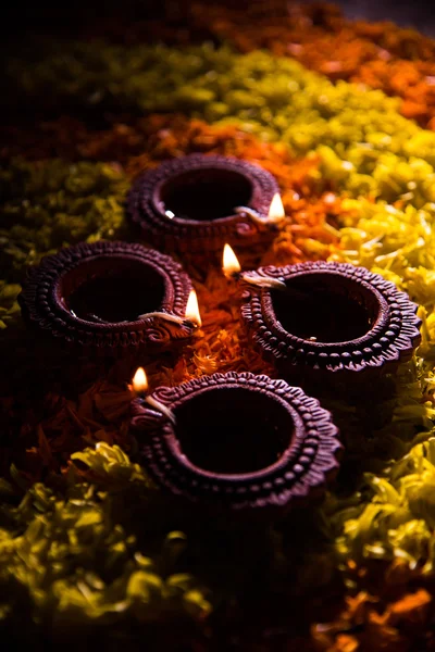Tradicional diya o lámpara de aceite encendido en rangoli colorido compuesto de pétalo de flor, en el festival de luces llamado diwali o deepawali, enfoque selectivo — Foto de Stock