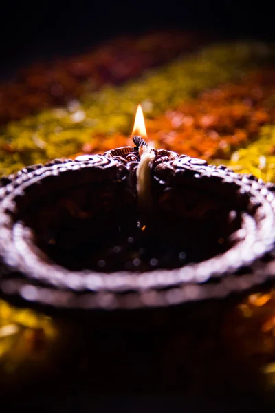 Lampada tradizionale a diya o olio accesa su colorati rangoli costituiti da petali di fiori, sulla festa delle luci chiamate diwali o deepawali, focus selettivo — Foto Stock