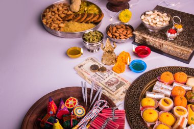 oil lamp or diya with crackers, sweet or mithai, dry fruits, indian currency notes, marigold flower and statue of Goddess Laxmi or lakshmi on diwali night clipart