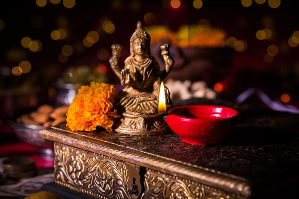 Lâmpada de óleo ou diya com biscoitos doces ou mithai, frutas secas, notas de moeda indiana, flor de calêndula e estátua da Deusa Laxmi ou lakshmi na noite de diwali — Fotografia de Stock