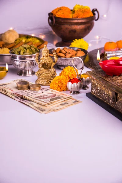 Lámpara de aceite o diya con galletas, dulces o mithai, frutas secas, billetes de moneda india, flor de caléndula y estatua de la Diosa Laxmi o lakshmi en la noche diwali — Foto de Stock