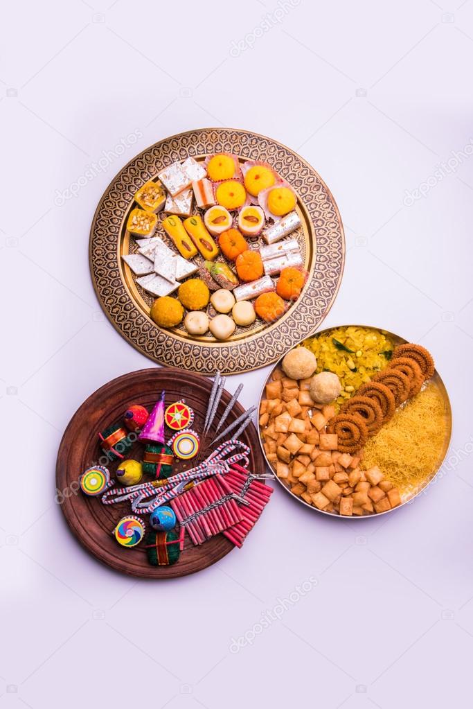 indian sweet food and fire crackers served in plate showing diwali concept