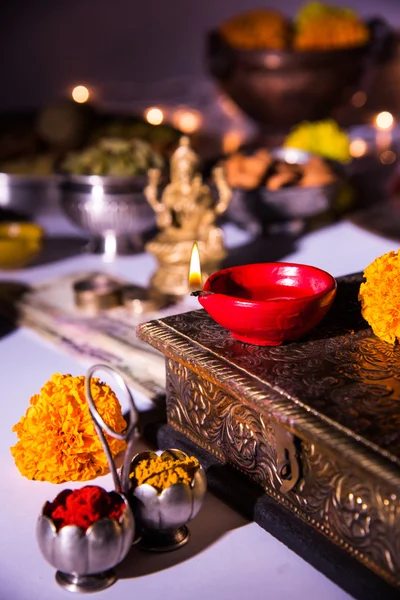 Lámpara de aceite o diya con galletas, dulces o mithai, frutas secas, billetes de moneda india, flor de caléndula y estatua de la Diosa Laxmi o lakshmi en la noche diwali — Foto de Stock