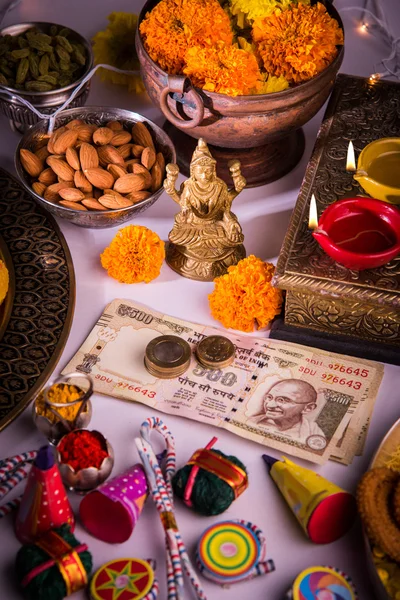 Oil lamp or diya with crackers, sweet or mithai, dry fruits, indian currency notes, marigold flower and statue of Goddess Laxmi or lakshmi on diwali night — Stock Photo, Image