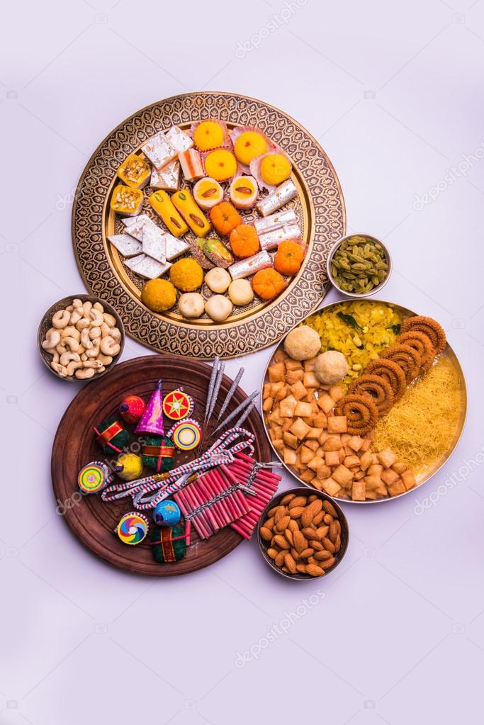 indian sweet food and fire crackers served in plate showing diwali concept