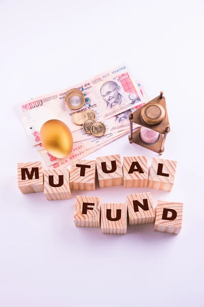 Indian currency notes with coins and golden egg along with antique sand clock and wooden blocks with MUTUAL FUNDS written over it — Stock Photo, Image