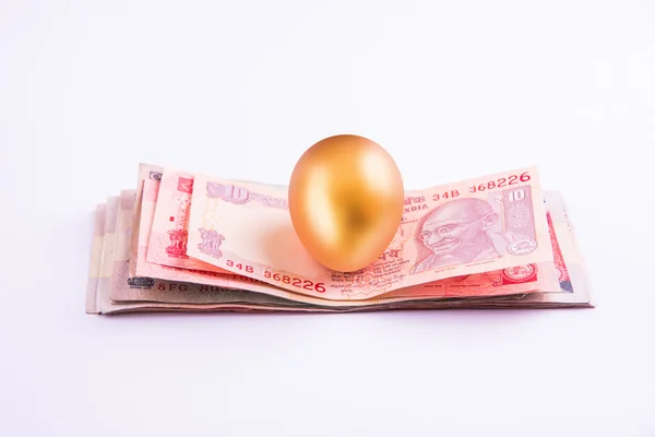 Un huevo de oro en una pila de billetes indios —  Fotos de Stock