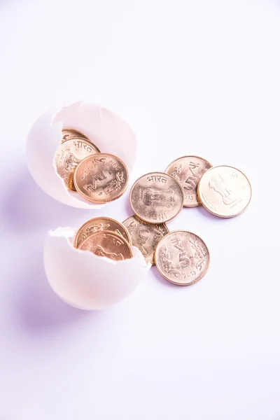 Monedas indias de cinco rupias que emergen de huevo agrietado, rupias indias y huevo agrietado, enfoque selectivo, aislado sobre fondo blanco — Foto de Stock