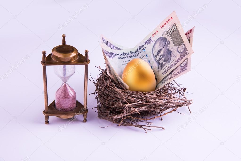 hourglass with Golden egg and indian money or indian currency note in a real nest. Shallow focus.