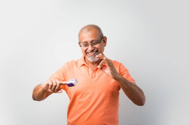 Hintli yaşlı ya da yaşlı adam termometre ve oksijen doygunluğunu oksimetre kullanarak kontrol ediyor.