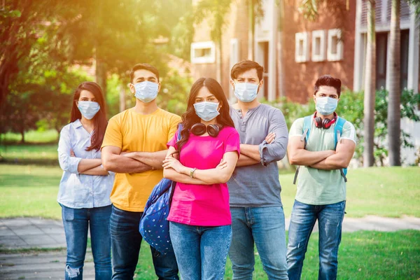 Asian Indian students wears face mask and follow social distancing norms in college or university campus after corona Pandemic unlock, focus on one student
