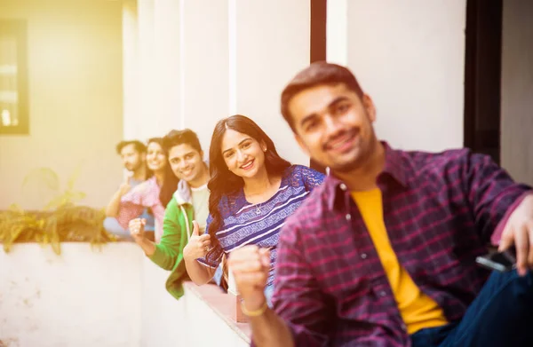 Asian Indian college students using smartphone while sitting in college campus, cel phone addiction