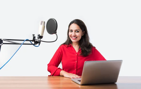 Pretty Indian woman speaks in front of microphone while recording a video blog for his subscribers, looking at camera