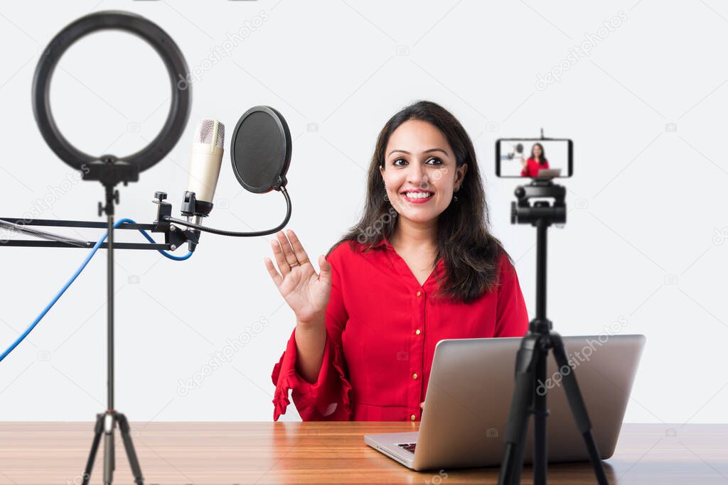 Pretty Indian woman speaks in front of microphone while recording a video blog for his subscribers, looking at camera