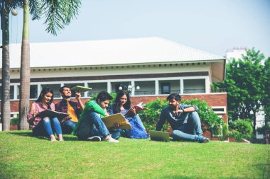 Genç Asyalı Hintli kolej öğrencileri kitap okuyor, dizüstü bilgisayarda çalışıyor, sınava hazırlanıyor ya da çim, merdiven ya da üniversite kampüsünün basamaklarında otururken grup projesi üzerinde çalışıyor.