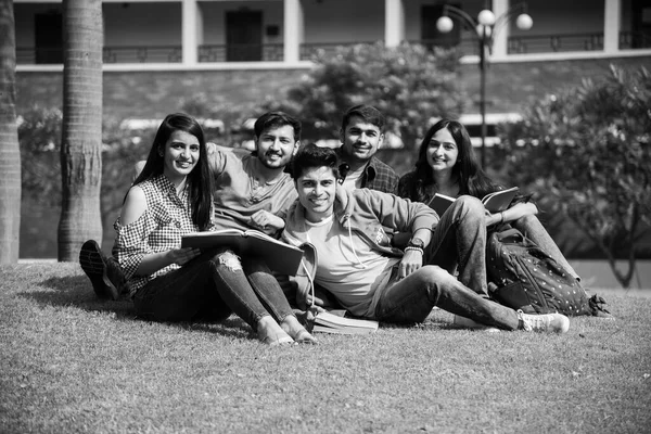 Cheerful Indian asian young group of college students or friends laughing together while sitting, standing or walking in campus