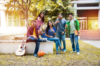 Asyalı Hintli kolej öğrencileri kampüsün açık alanlarında birlikte kahve içiyorlar. Muhabbet ediyorduk.