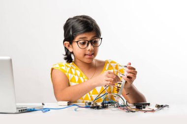 Elektronik deney - Asyalı Hintli küçük kız öğrenci kablolarla, bağlantılarla, dizüstü bilgisayarla veya tablet bilgisayarla bilim yapıyor veya okuyor