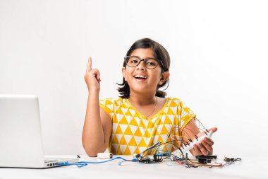 Elektronik deney - Asyalı Hintli küçük kız öğrenci kablolarla, bağlantılarla, dizüstü bilgisayarla veya tablet bilgisayarla bilim yapıyor veya okuyor