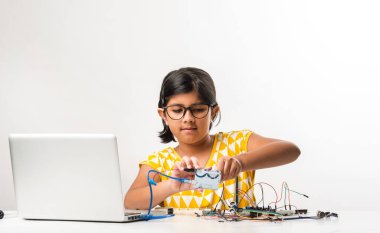Elektronik deney - Asyalı Hintli küçük kız öğrenci kablolarla, bağlantılarla, dizüstü bilgisayarla veya tablet bilgisayarla bilim yapıyor veya okuyor