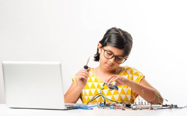 Elektronik deney - Asyalı Hintli küçük kız öğrenci kablolarla, bağlantılarla, dizüstü bilgisayarla veya tablet bilgisayarla bilim yapıyor veya okuyor