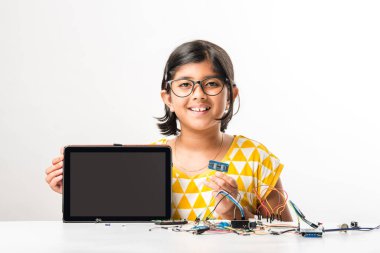 Elektronik deney - Asyalı Hintli küçük kız öğrenci kablolarla, bağlantılarla, dizüstü bilgisayarla veya tablet bilgisayarla bilim yapıyor veya okuyor