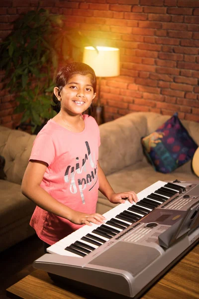 Asian Indian child learning music or musical instrument online using laptop computer or tablet at home, persuing hobby