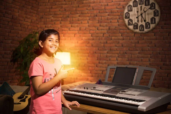 Asian Indian child learning music or musical instrument online using laptop computer or tablet at home, persuing hobby