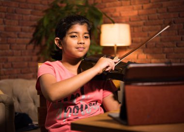 Asyalı Hintli çocuk evde bilgisayar ya da tablet kullanarak müzik ya da müzik aleti öğreniyor, hobiyi ikna ediyor
