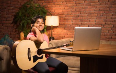 Asyalı Hintli çocuk evde bilgisayar ya da tablet kullanarak müzik ya da müzik aleti öğreniyor, hobiyi ikna ediyor