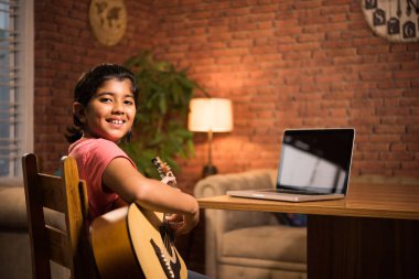 Asyalı Hintli çocuk evde bilgisayar ya da tablet kullanarak müzik ya da müzik aleti öğreniyor, hobiyi ikna ediyor