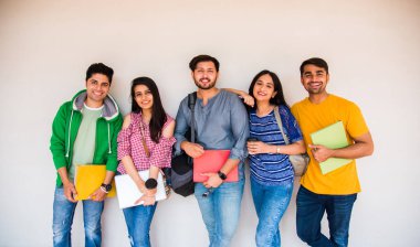 Kolej öğrencilerinden oluşan neşeli Hintli genç bir grup ya da arkadaşlar kampüste otururken, ayakta ya da yürürken birlikte gülüyorlar.