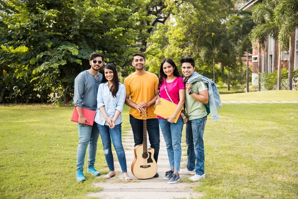 Cheerful Indian asian young group of college students or friends laughing together while sitting, standing or walking in campus