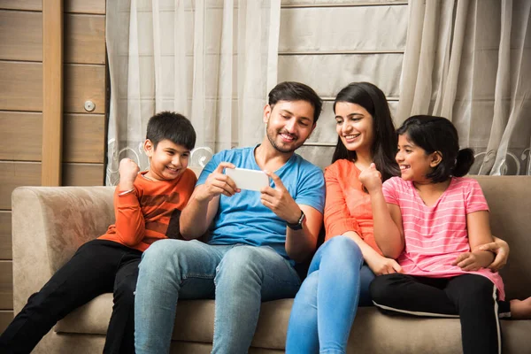 Indian Family Sitting Sofa Using Smartphone Laptop Tablet Watching Movie — Stock Photo, Image