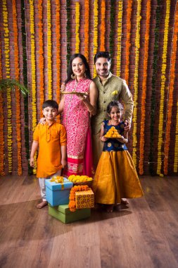 Diwali veya Rakshabandhan Kutlaması - Dört kişilik Hint ailesi Deepavali veya Bhai Dooj festivalini tatlı laddoo, yağ lambası ve şeker ve şeker kutuları ile kutluyor, yemek yiyor veya selfie çekiyor