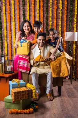 Diwali veya Rakshabandhan Kutlaması - Dört kişilik Hint ailesi Deepavali veya Bhai Dooj festivalini tatlı laddoo, yağ lambası ve şeker ve şeker kutuları ile kutluyor, yemek yiyor veya selfie çekiyor