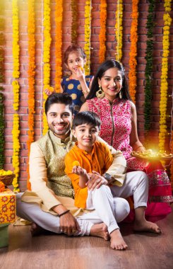 Diwali veya Rakshabandhan Kutlaması - Dört kişilik Hint ailesi Deepavali veya Bhai Dooj festivalini tatlı laddoo, yağ lambası ve şeker ve şeker kutuları ile kutluyor, yemek yiyor veya selfie çekiyor